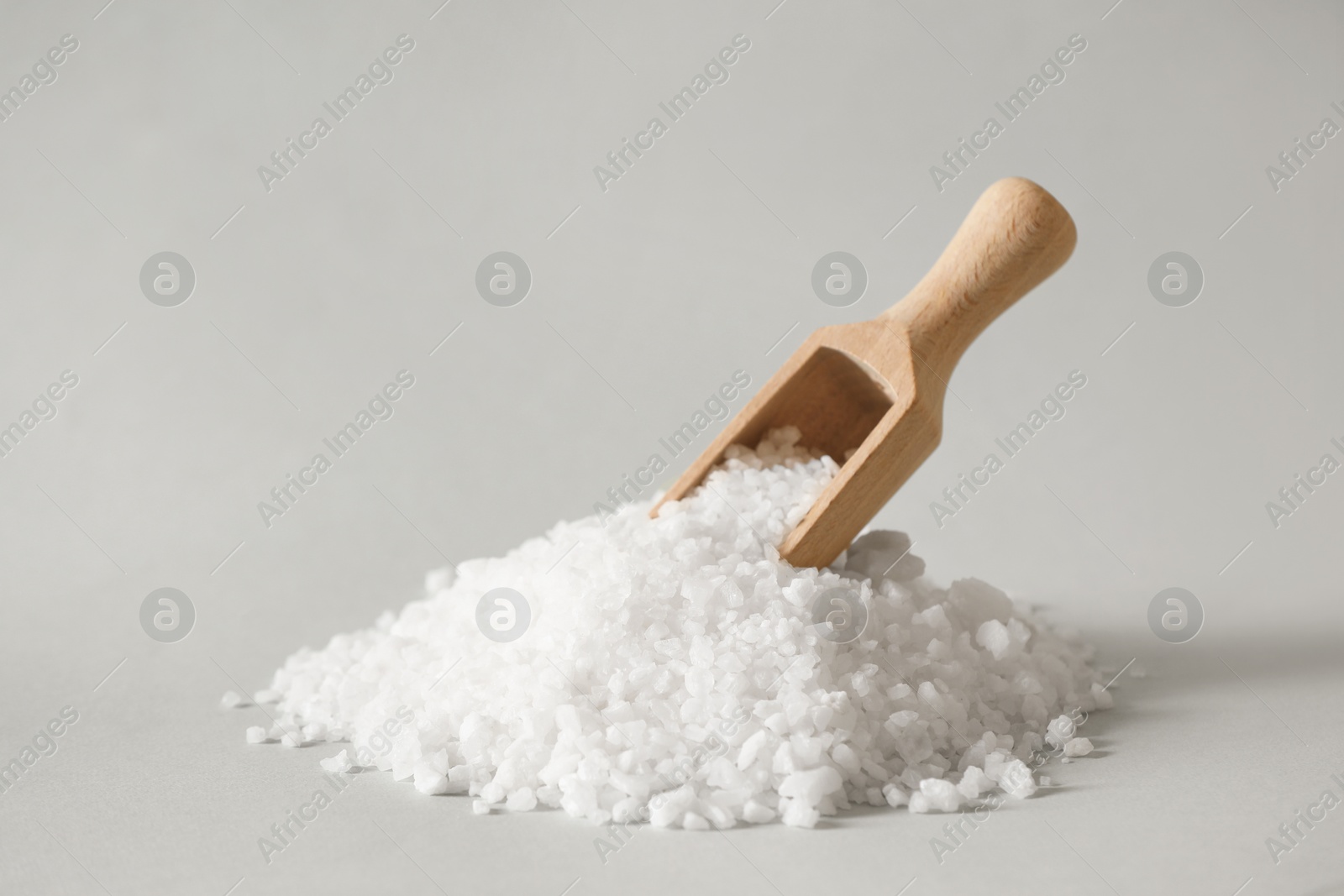 Photo of Organic salt and wooden scoop on light grey background