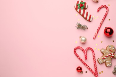 Flat lay composition with sweet candy canes and Christmas decor on pink background, space for text