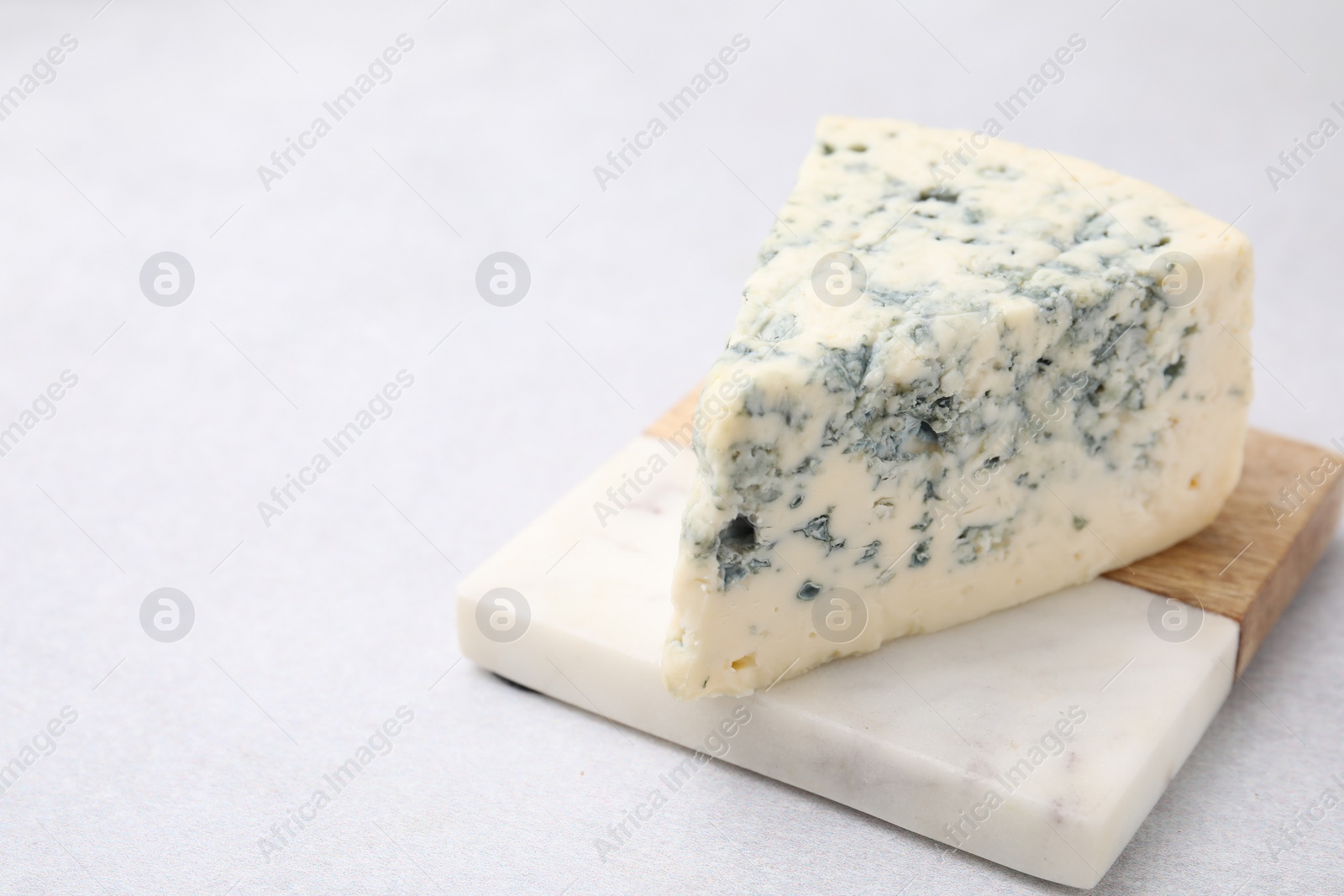 Photo of Tasty blue cheese on light table. Space for text