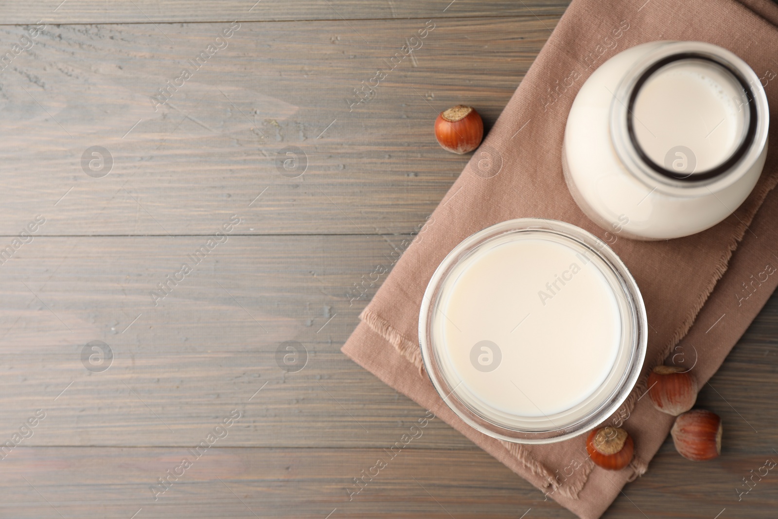 Photo of Glassware with lactose free milk and hazelnuts on wooden table, top view. Space for text