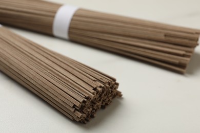 Photo of Uncooked buckwheat noodles (soba) on white marble table, closeup