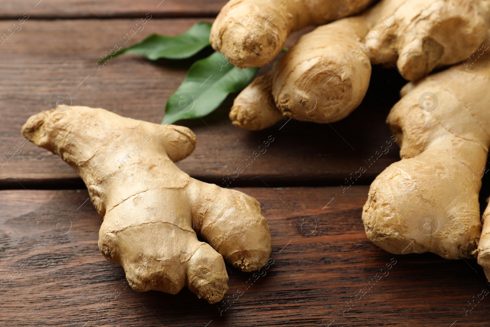 Photo of Fresh ginger with leaves on wooden table, closeup