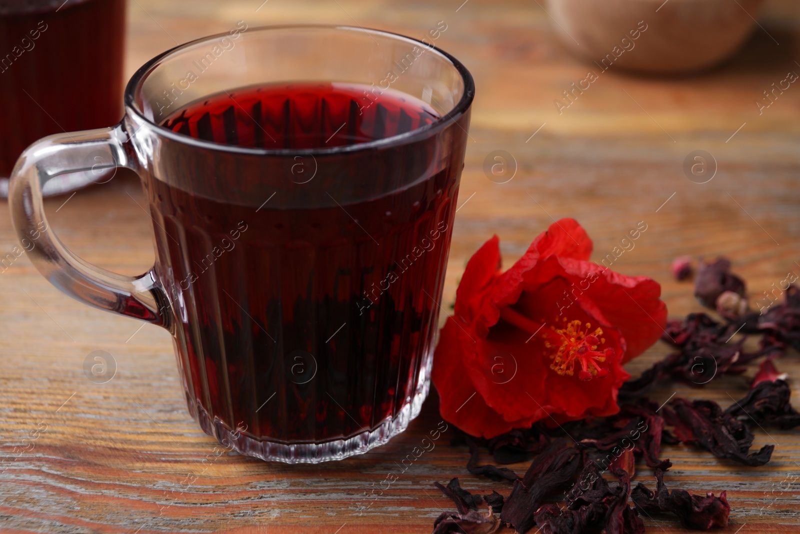 Photo of Delicious hibiscus tea and flower on wooden table, closeup