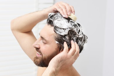 Photo of Happy man washing his hair with shampoo in shower