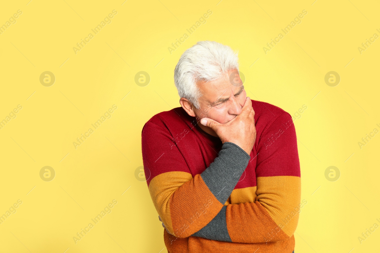 Image of Senior man suppressing cough on yellow background. Cold symptoms