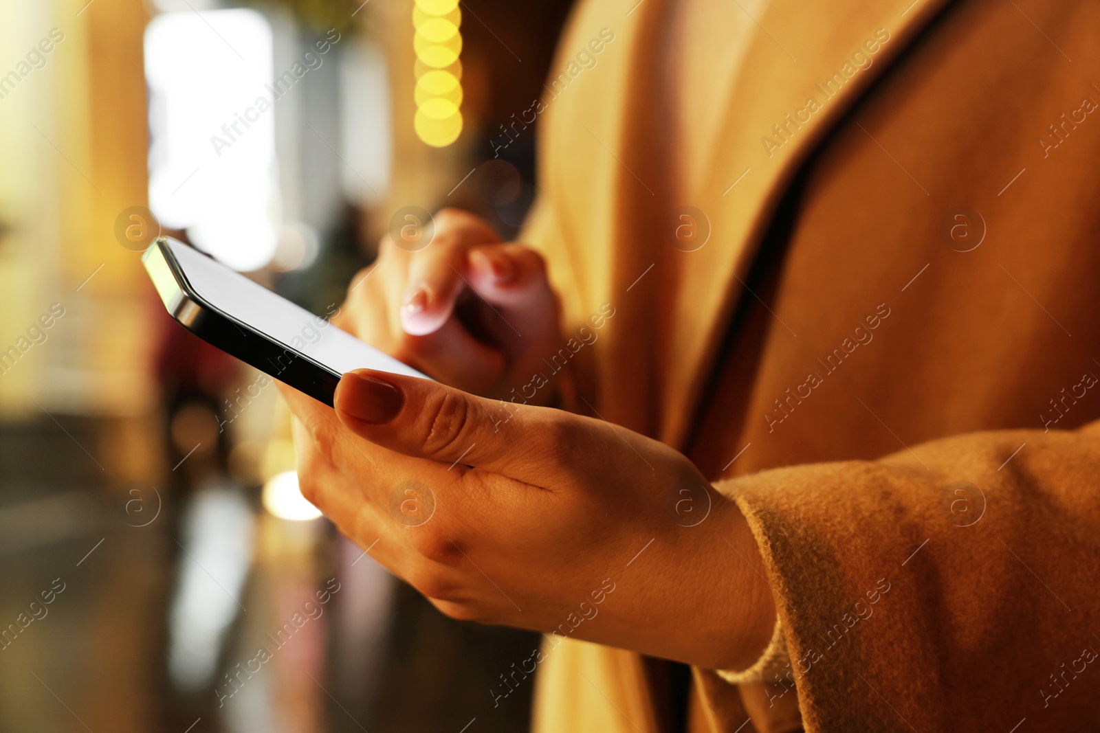 Photo of Woman using smartphone on night city street, closeup