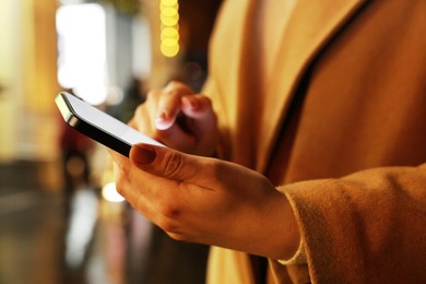 Woman using smartphone on night city street, closeup