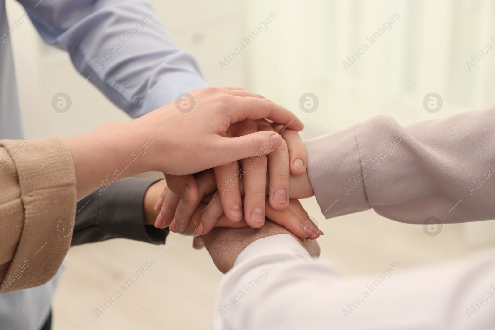 Photo of Group of people holding their hands together on blurred background, closeup