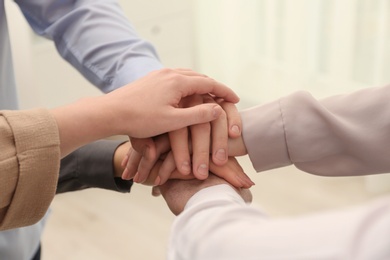 Photo of Group of people holding their hands together on blurred background, closeup