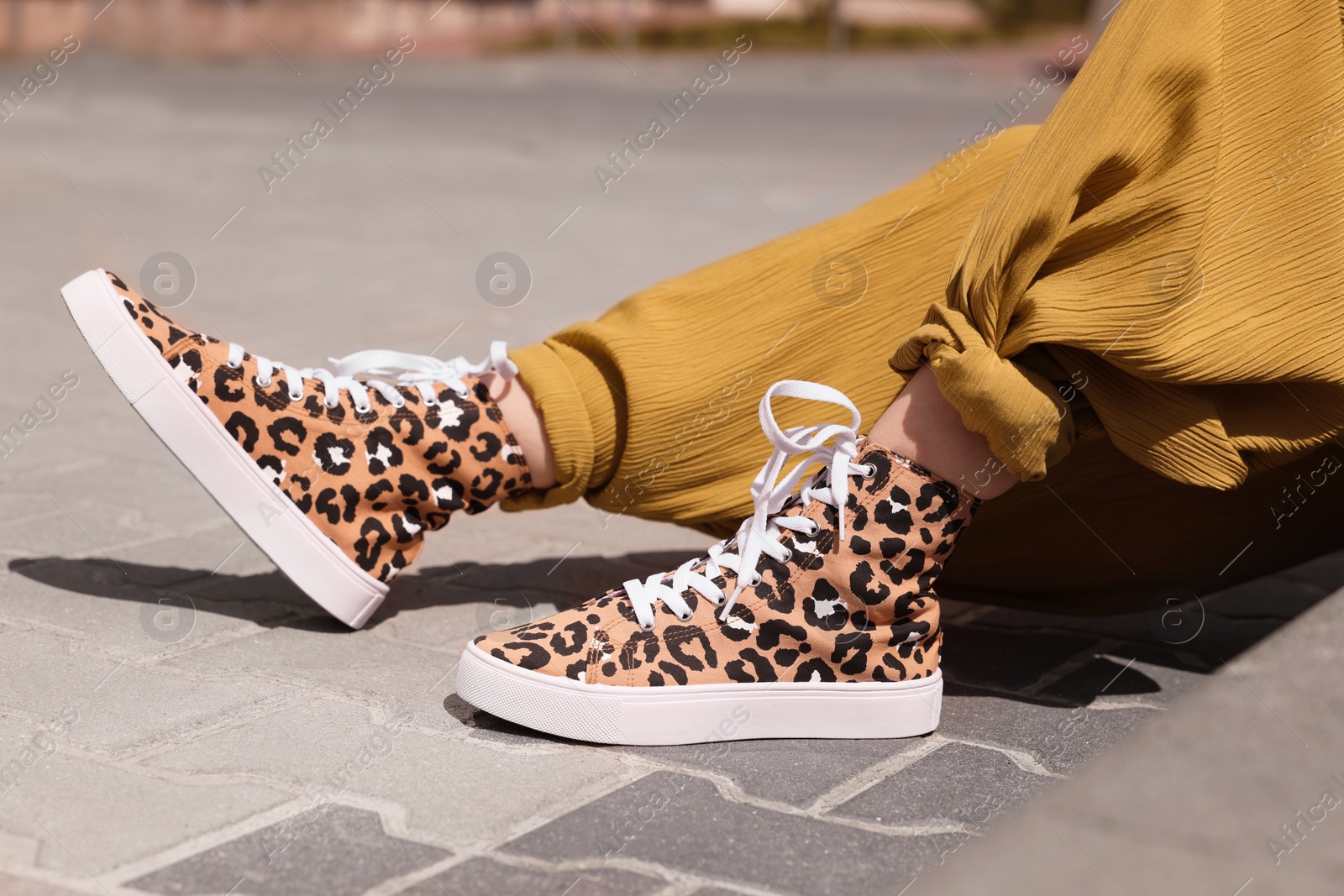 Photo of Woman wearing sneakers with leopard print outdoors, closeup