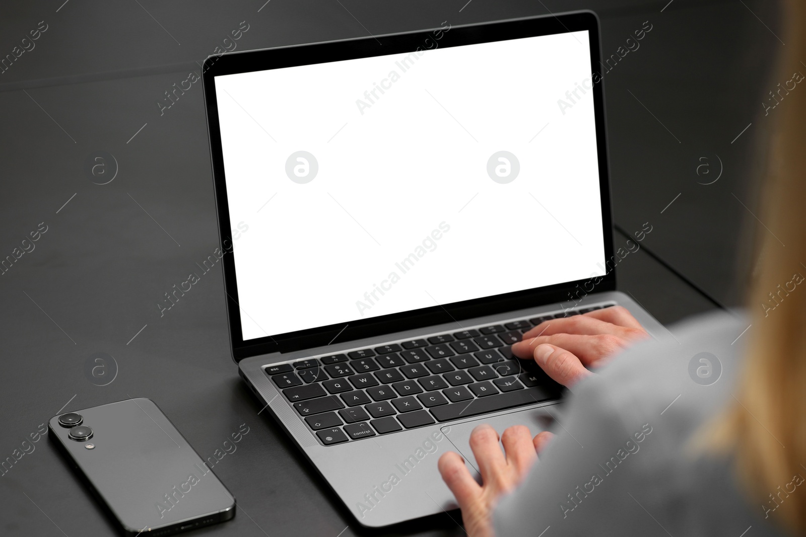 Photo of Woman working on laptop at black desk in office, closeup