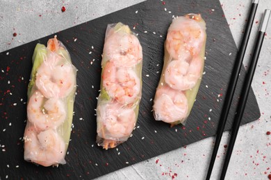 Photo of Tasty spring rolls served with spices on grey textured table, flat lay