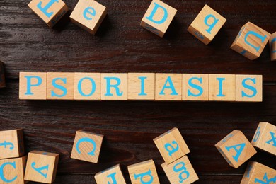 Photo of Word Psoriasis made of cubes with letters on wooden table, flat lay