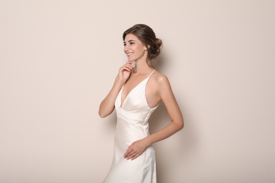 Photo of Young bride wearing beautiful wedding dress on beige background
