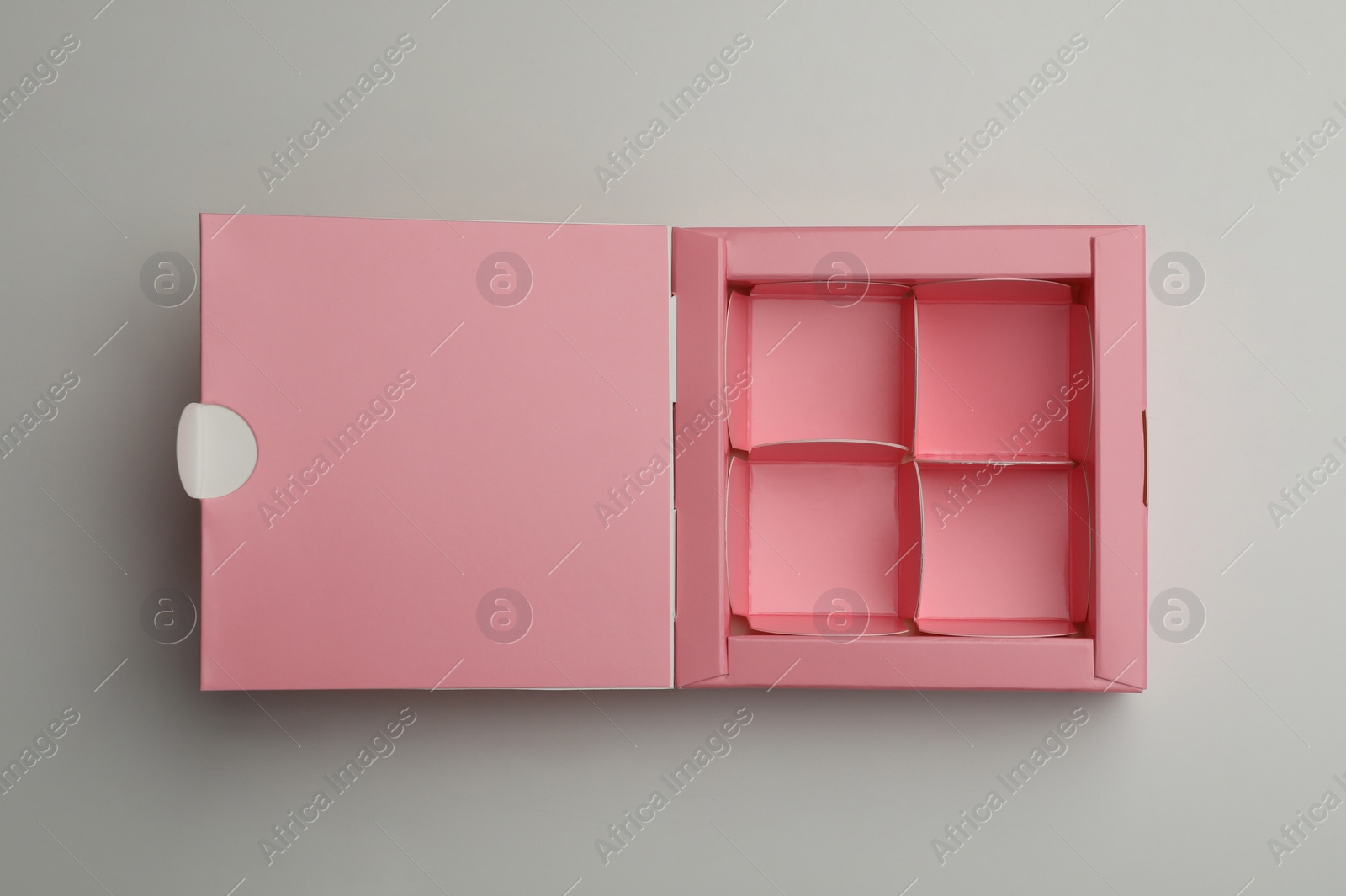 Photo of Empty pink box for candies on light grey background, top view