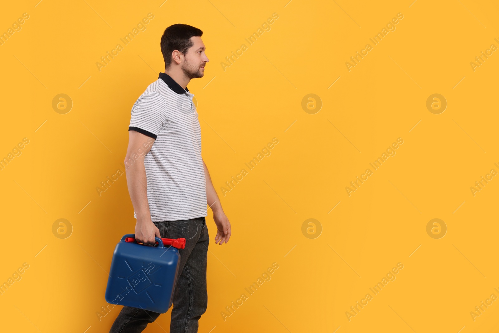 Photo of Man holding blue canister on orange background. Space for text