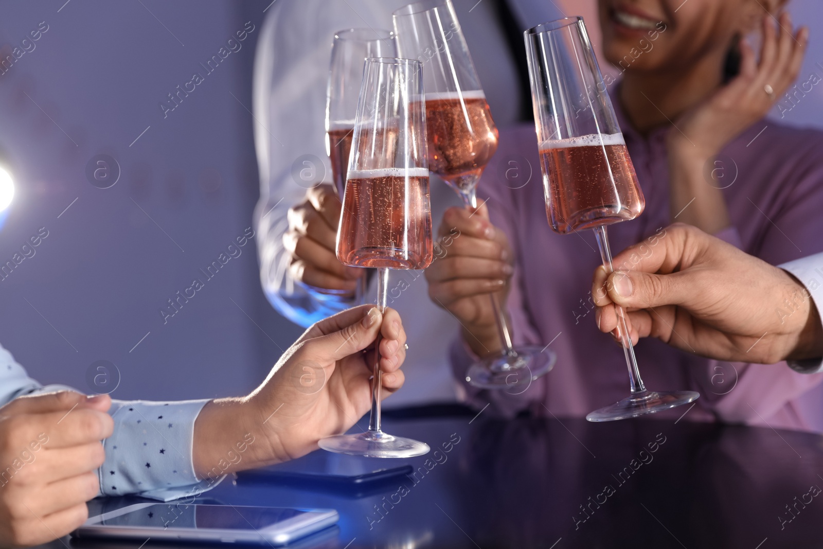 Photo of Friends clinking glasses of champagne at table in restaurant, closeup