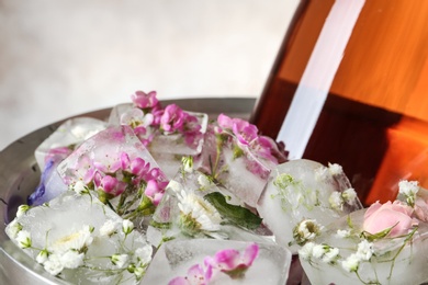 Floral ice cubes and bottle of champagne in bucket, closeup