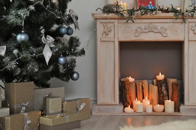 Decorative fireplace and Christmas tree with gift boxes in stylish living room interior