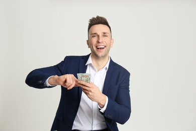 Happy man throwing money on light grey background