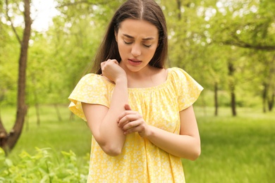 Young woman scratching hand outdoors. Seasonal allergy