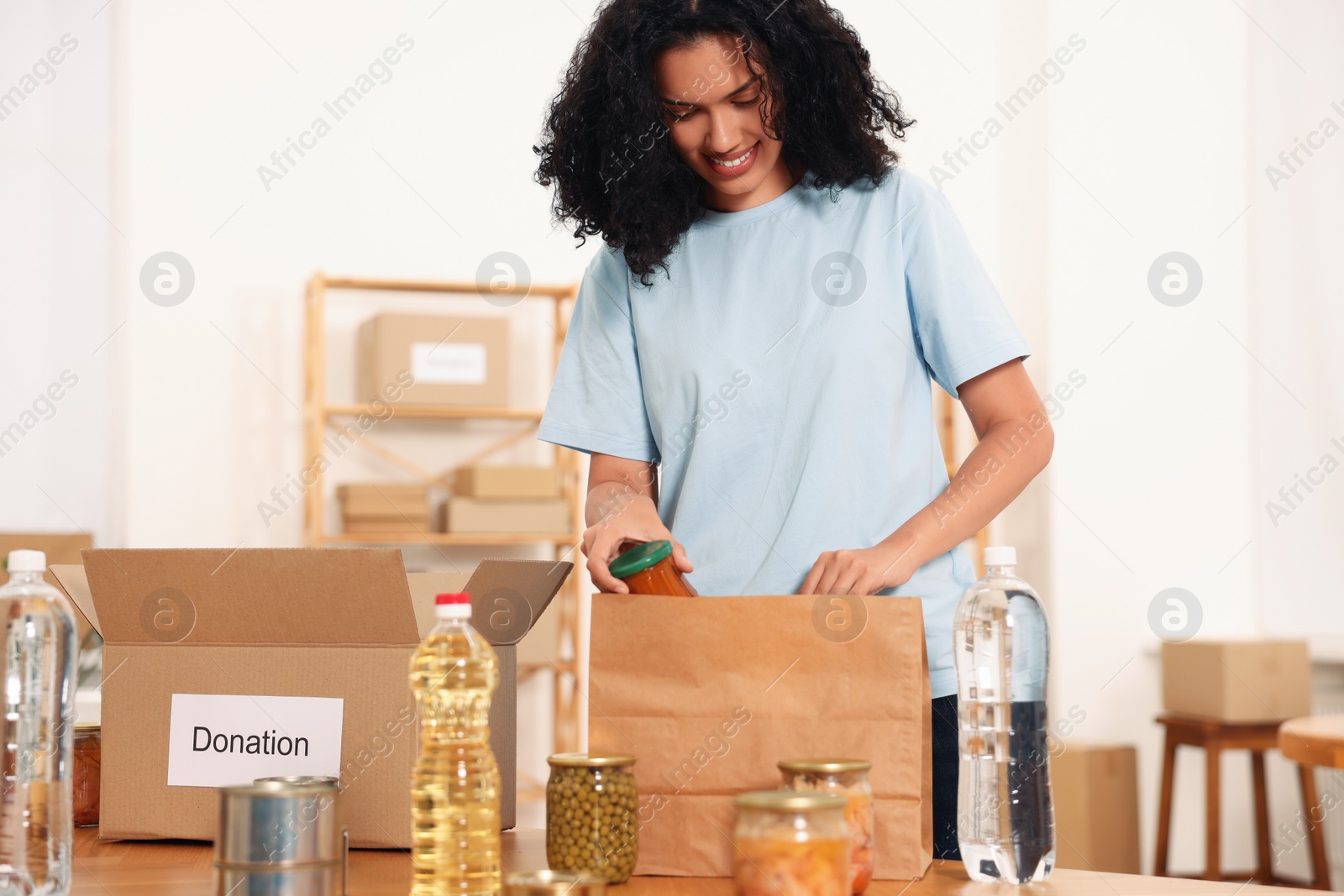Photo of Volunteer packing food products at table in warehouse