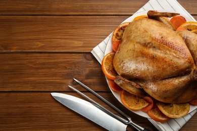 Delicious chicken with oranges on wooden table, flat lay. Space for text