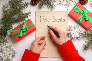 Top view of woman writing letter to Santa at white table, closeup