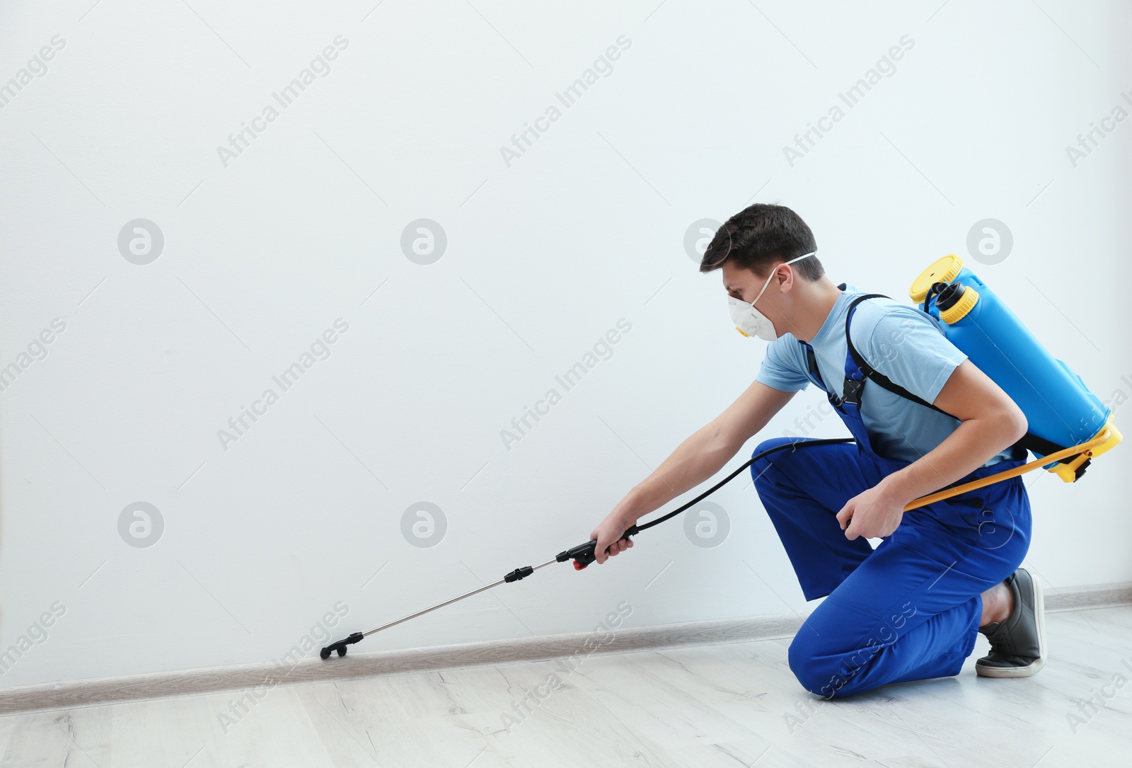 Photo of Pest control worker spraying pesticide in room. Space for text