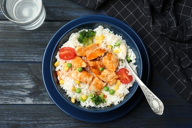 Boiled rice with vegetables and meat served on wooden table, flat lay