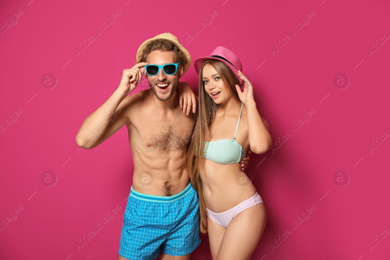 Photo of Happy young couple in beachwear on color background