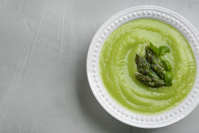 Delicious asparagus soup on grey table, top view. Space for text