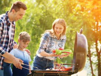 Happy family having barbecue with modern grill outdoors on sunny day