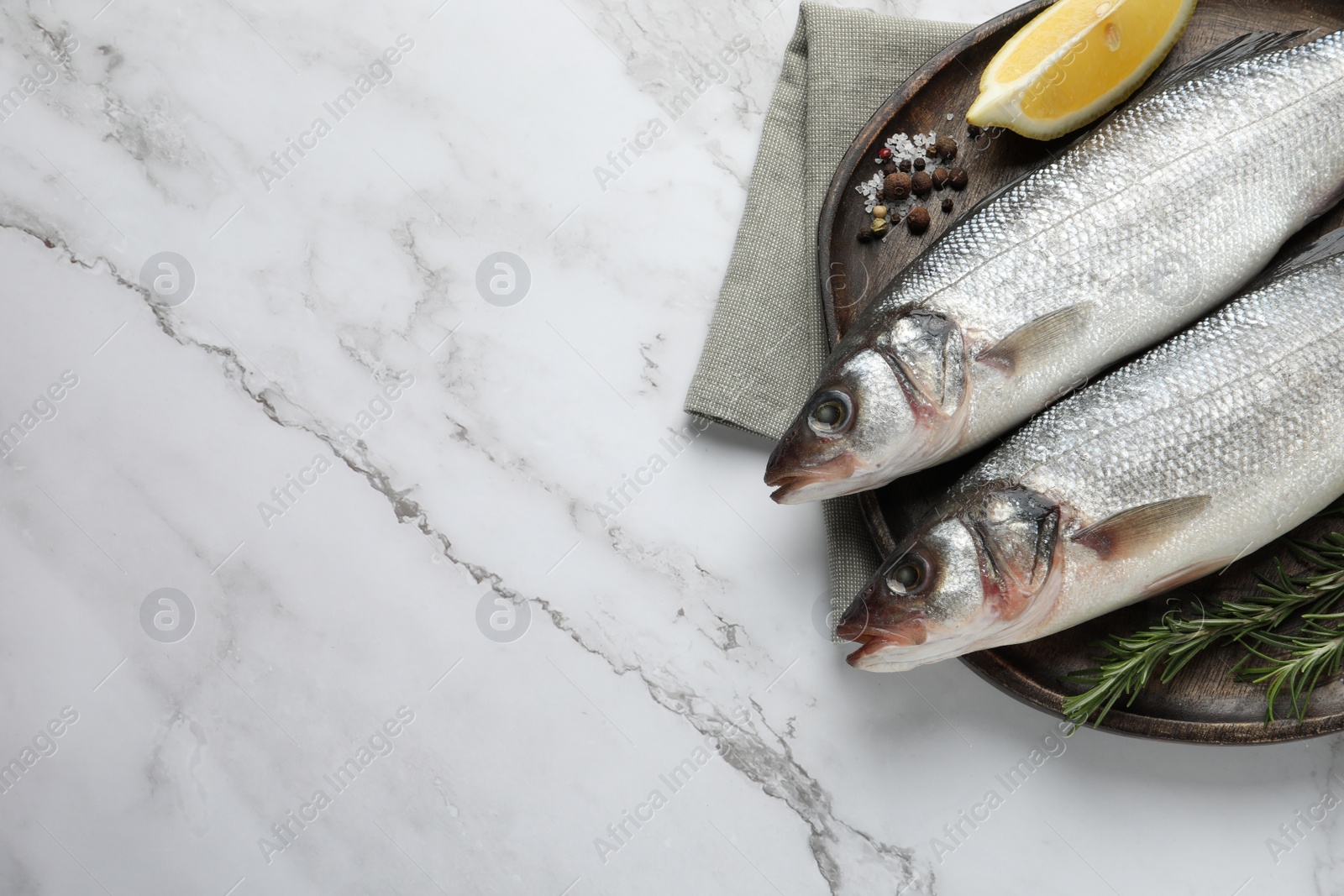 Photo of Tasty sea bass fish and spices on white marble table, top view. Space for text