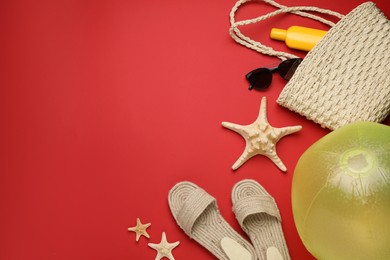 Flat lay composition with ball and beach objects on red background, space for text