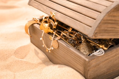 Photo of Open wooden treasure chest on sand, closeup