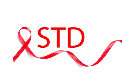 Image of Red awareness ribbon and abbreviation STD on white background, top view 