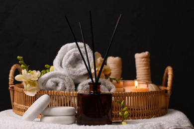 Photo of Aromatic reed air freshener, rolled towels and spa stones on table