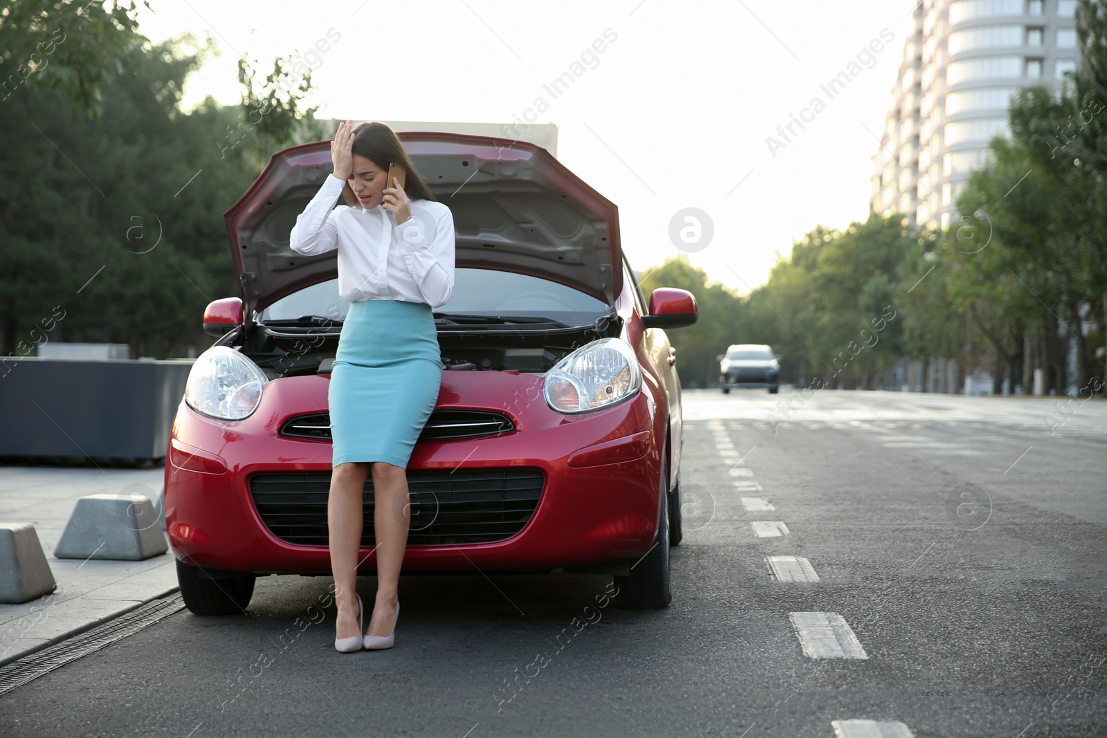 Photo of Stressed woman talking on phone near broken car outdoors