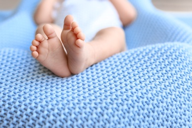 Photo of Cute little baby lying on light blue plaid, closeup. Space for text
