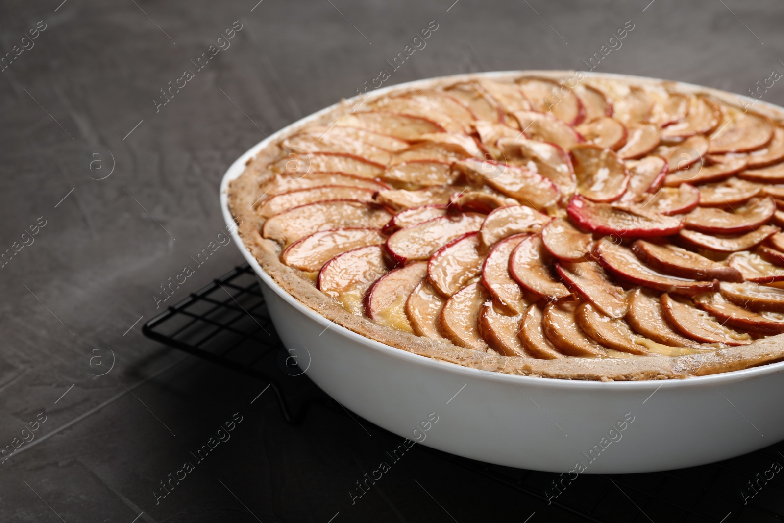 Photo of Tasty apple pie in baking dish on grey table, closeup