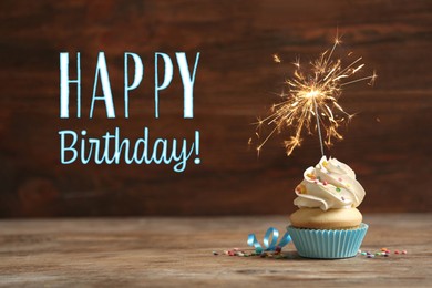 Image of Happy Birthday! Delicious cupcake with sparkler on wooden table