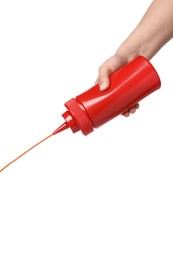 Woman pouring tasty ketchup from bottle on white background, closeup