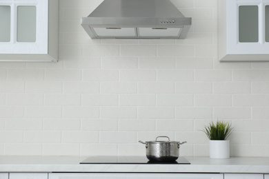 Photo of Saucepot on induction stove in stylish kitchen interior