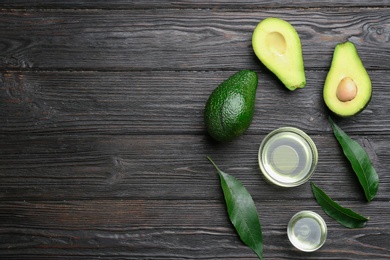 Photo of Bowls of natural oil and avocados on black wooden background, flat lay. Space for text