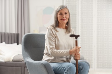 Photo of Mature woman with walking cane in armchair at home