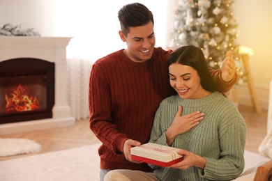 Boyfriend giving Christmas gift box to his girlfriend at home