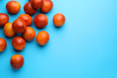 Photo of Many ripe sicilian oranges on light blue background, flat lay. Space for text