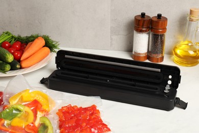 Photo of Sealer for vacuum packing and different products on white table indoors
