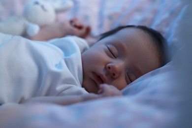 Photo of Cute newborn baby sleeping in crib at night, closeup